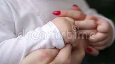 关爱母亲与婴儿，爱和家庭的概念。 母亲和婴儿的手特写，手牵手。 母亲照料